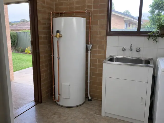 Newly installed hot water cylinder beside a laundry tub and tiled wall in Gateshead